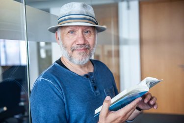 Der Verleger Günter Butkus im blauen Shirt mit Buch und Hut
